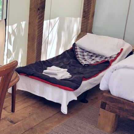 Rental cot set up inside a glamping tent at NATURA Wilderness Resort in Nova Scotia