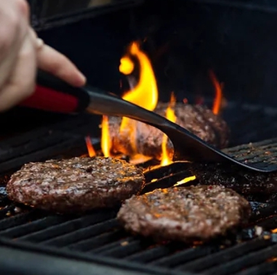 Burgers cooking over a campfire grill at a glamping campsite