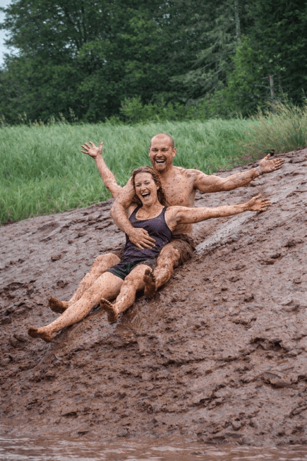 Visitors sliding through tidal bore mud along the Shubenacadie River after a Fundy tidal bore rafting adventure